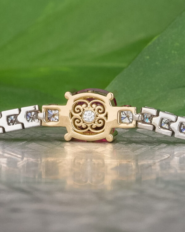 The "Araceli" Bracelet in 14K white and 18K yellow gold with 2.96-carat spinel Close-up of The "Araceli" Bracelet in 14K white and yellow gold, featuring a 2.96-carat spinel and a central ornate round design, displayed on a reflective surface with a green leaf background—ideal for bracelet stacking.