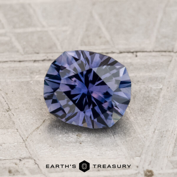 1.18-Carat Montana Sapphire (Heated) A 1.18-carat heated Montana sapphire rests on a textured gray surface with the text “EARTH'S TREASURY” displayed below.