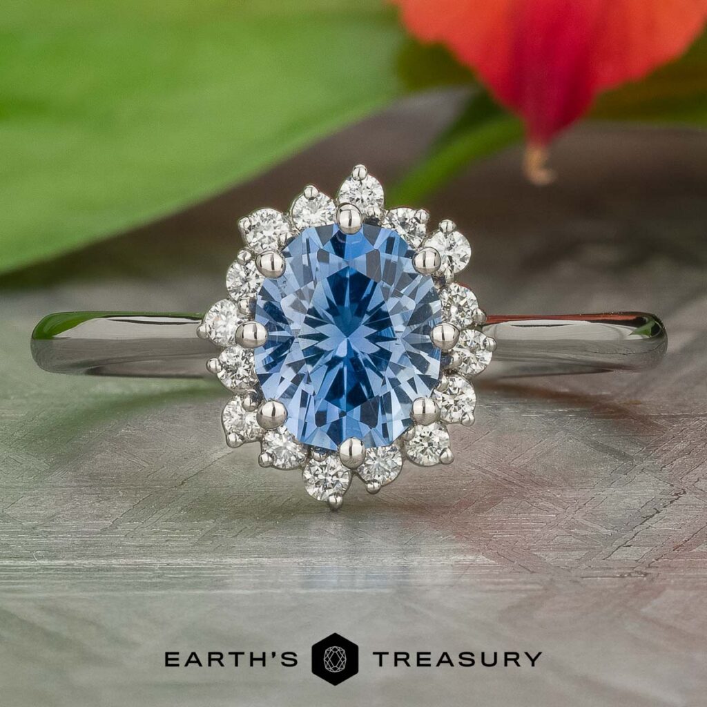 A silver ring with an oval blue gemstone surrounded by small round diamonds is displayed on a flat surface, labeled "Stacked from 18 images. Method=B (R=14,S=2)" below.