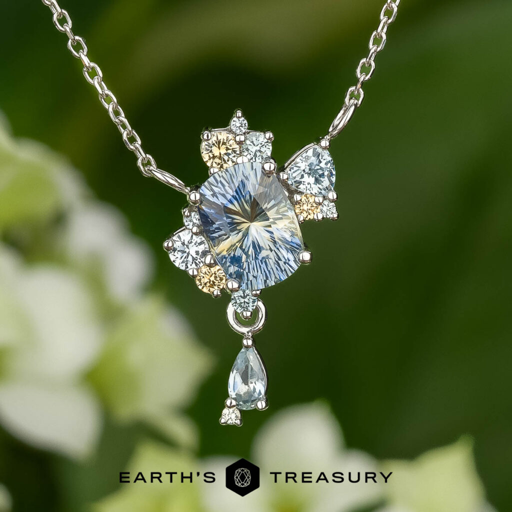 Stacked from 16 images, this necklace features a rectangular faceted gemstone pendant with smaller clear and pale blue stones. The "EARTH'S TREASURY" logo appears at the bottom. Method=B (R=14,S=2).