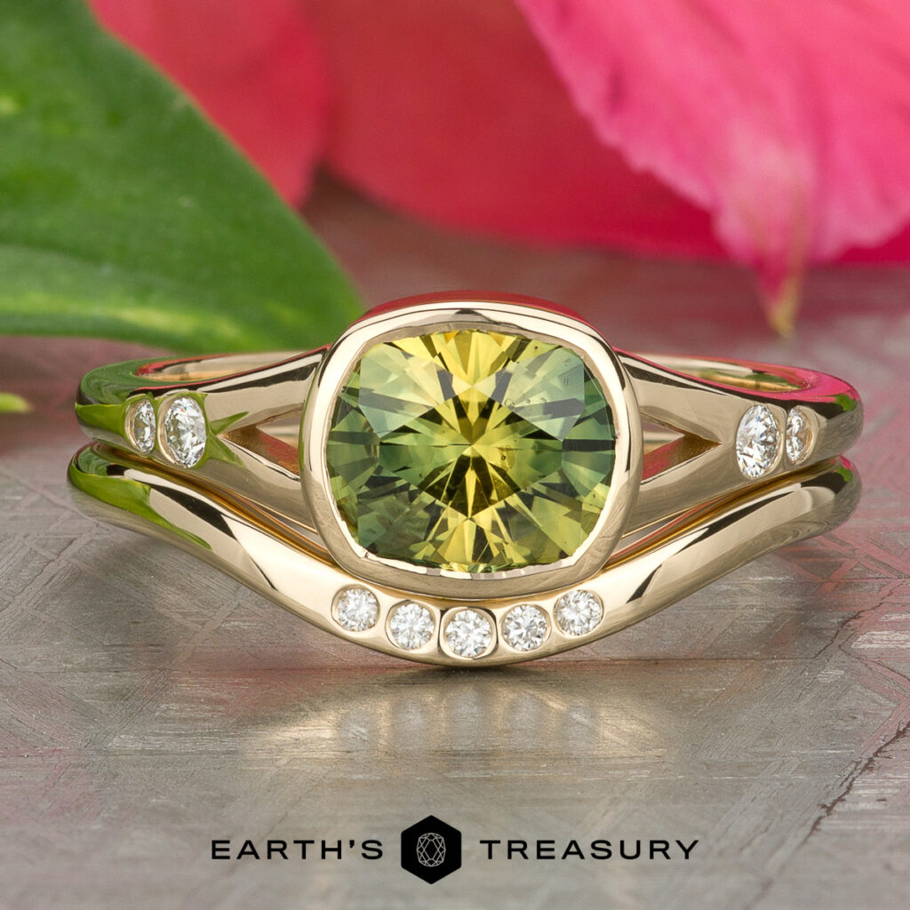 A gold ring featuring a greenish-yellow gemstone and small diamonds rests on a textured surface with pink and green leaves. The text reads: "Stacked from 20 images. Method=B (R=14, S=2).
