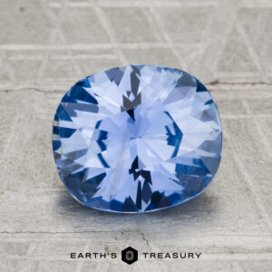 A 2.88-carat Ceylon sapphire with a cushion cut is shown on a textured gray surface, featuring the "Earth's Treasury" text below.