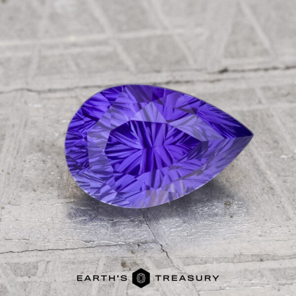 2.04-Carat Ceylon Sapphire A 2.04-carat Ceylon sapphire, pear-shaped and faceted in purple, rests on a textured light gray surface with "EARTH'S TREASURY" below.