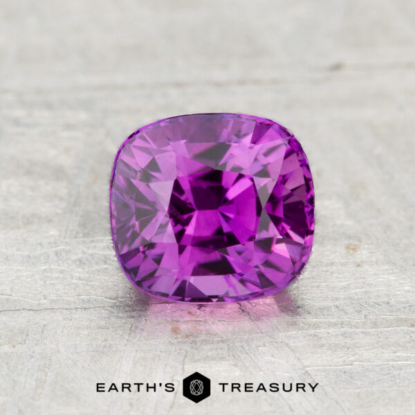 A 1.18-carat cushion-cut Ceylon sapphire (heated) is showcased on a textured gray surface with the "Earth's Treasury" logo below it.