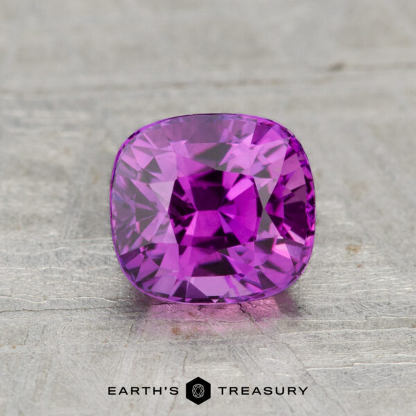 1.18-Carat Ceylon Sapphire (Heated) A 1.18-carat cushion-cut Ceylon sapphire (heated) is showcased on a textured gray surface with the "Earth's Treasury" logo below it.