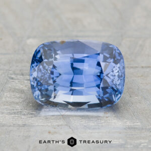 A 3.13-carat Ceylon sapphire, cushion-cut in a rectangular shape, displayed on a textured surface with "EARTH'S TREASURY" shown below.