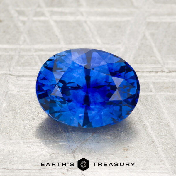 2.07-Carat Ceylon Sapphire (Heated) A 2.07-carat heated Ceylon sapphire, faceted in an oval shape, displayed on a textured surface with "Earth's Treasury" at the bottom.
