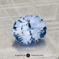 A 2.24-carat Ceylon Sapphire, round brilliant-cut and blue, is displayed on a textured metallic surface with the "EARTH'S TREASURY" logo and text at the bottom.