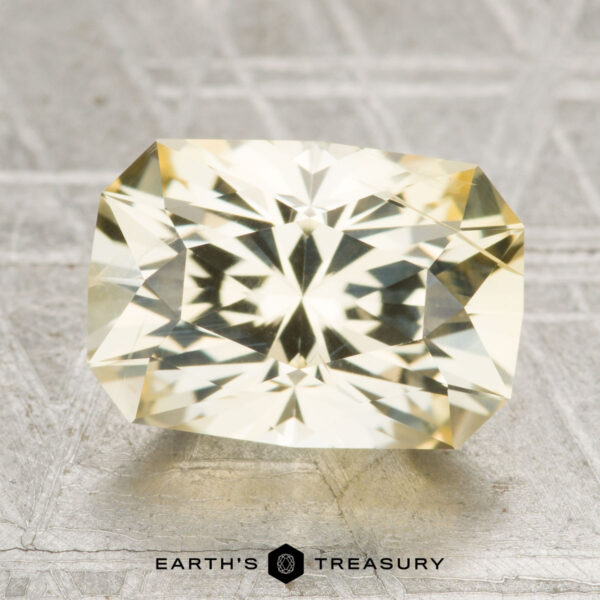 4.87-Carat Ceylon Sapphire A 4.87-carat Ceylon sapphire, cut in a rectangular faceted shape, rests on a textured gray surface with "Earth's Treasury" written below.