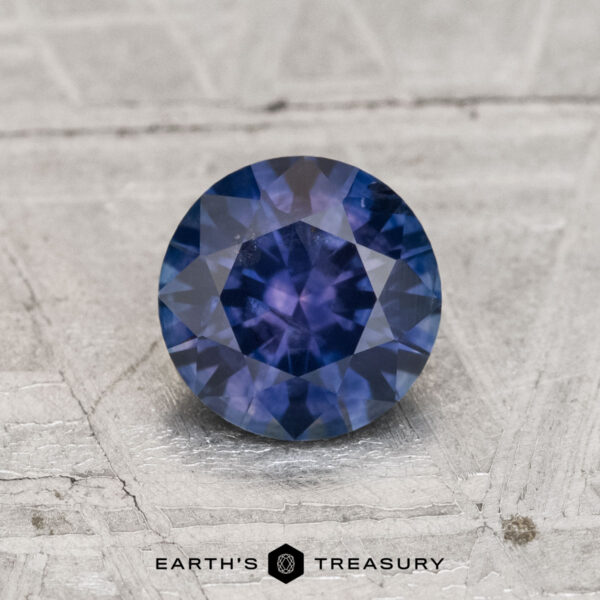 1.04-Carat Montana Sapphire (Heated) A 1.04-Carat Montana Sapphire (Heated) is shown on a textured gray surface, with "Earth's Treasury" featured at the bottom.