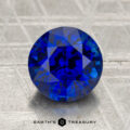 A 2.77-carat heated Ceylon sapphire, round brilliant-cut, sits on a textured metallic surface with "EARTH'S TREASURY" visible below.