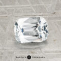 A 2.03-carat heated Ceylon sapphire, cut in a rectangular cushion shape, is showcased on a textured gray surface with "EARTH'S TREASURY" at the bottom.