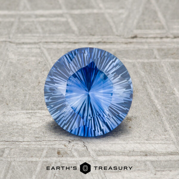 1.02-Carat Ceylon Sapphire (Heated) A 1.02-carat Ceylon sapphire (heated), round and faceted, is displayed on a textured gray surface with "EARTH'S TREASURY" at the bottom.