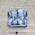 A 2.32-carat Ceylon sapphire, square-cut with intricate facets, rests on a textured gray surface. The "EARTH'S TREASURY" logo and text are featured at the bottom.
