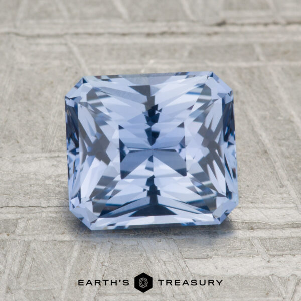 2.32-Carat Ceylon Sapphire A 2.32-carat Ceylon sapphire, square-cut with intricate facets, rests on a textured gray surface. The "EARTH'S TREASURY" logo and text are featured at the bottom.