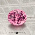 A round, faceted 1.56-carat Madagascar pink sapphire is displayed on a textured gray background with the words "Earth's Treasury" at the bottom.