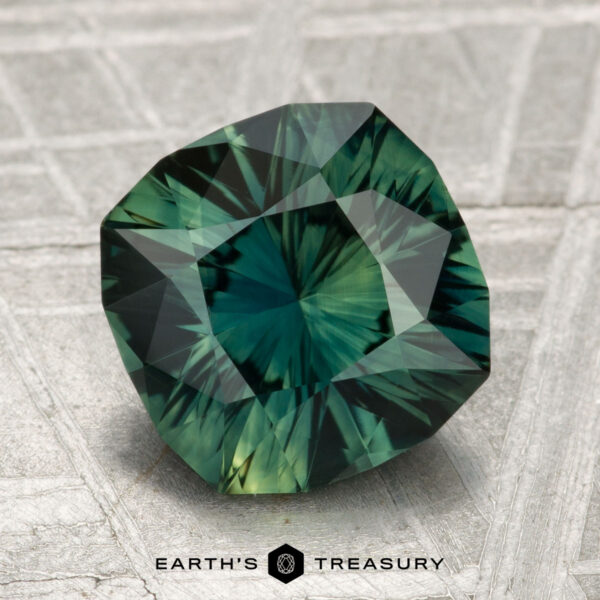 3.24-Carat Sapphire A 3.24-carat faceted green sapphire with intricate internal patterns is displayed on a textured surface, with the "Earth's Treasury" logo at the bottom.