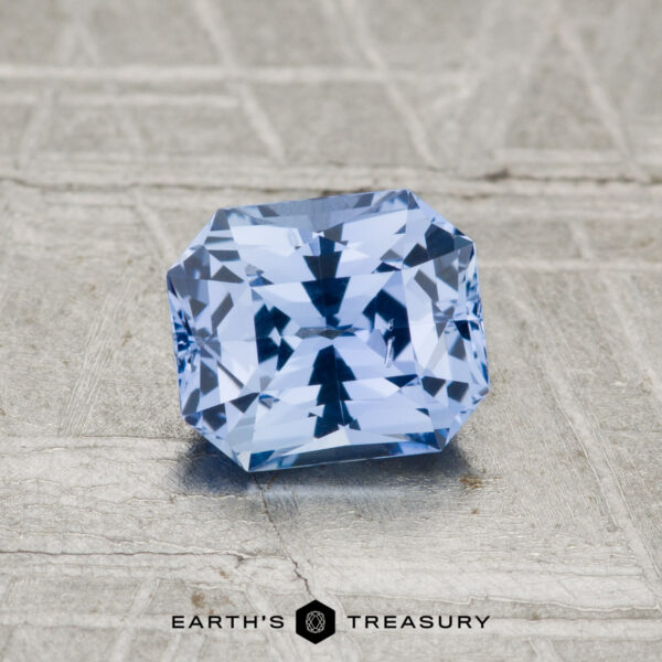 1.12-Carat Ceylon Sapphire A 1.12-carat Ceylon sapphire with a rectangular facet is displayed on a textured gray surface, with "EARTH'S TREASURY" printed below.