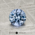 A 1.37-carat Ceylon sapphire, round brilliant-cut and blue, is displayed on a textured gray surface with the text "Earth's Treasury" below.