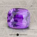A 3.06-carat Ceylon sapphire, cushion-cut and purple, displayed on a light textured surface with the text "EARTH'S TREASURY" at the bottom.