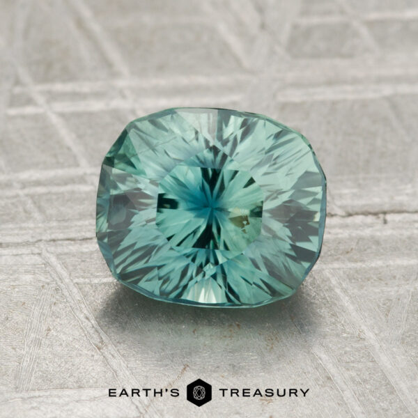2.16-Carat Sapphire A 2.16-carat sapphire is displayed on a textured, pale surface with the text "EARTH'S TREASURY" at the bottom.