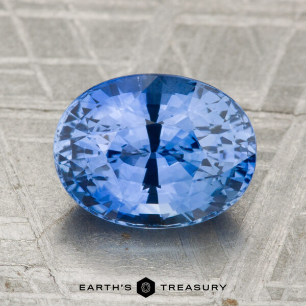 3.06-Carat Ceylon Sapphire (Heated) A 3.06-carat heated Ceylon sapphire is displayed on a textured metallic surface labeled "Earth's Treasury.