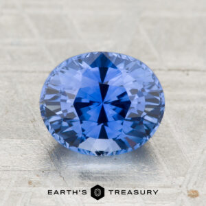A 2.29-carat heated Ceylon sapphire with an oval cut is displayed on a textured surface, with "EARTH'S TREASURY" featured below.