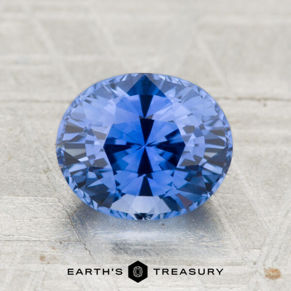2.29-Carat Ceylon Sapphire (Heated) A 2.29-carat heated Ceylon sapphire with an oval cut is displayed on a textured surface, with "EARTH'S TREASURY" featured below.