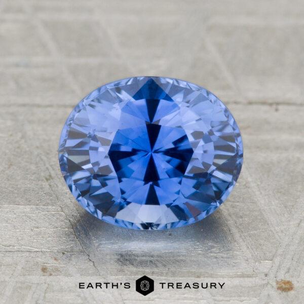 2.29-Carat Ceylon Sapphire (Heated) A 2.29-carat heated Ceylon sapphire with an oval cut is displayed on a textured surface, with "EARTH'S TREASURY" featured below.