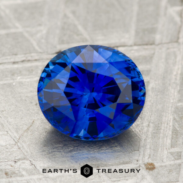 2.18-Carat Ceylon Sapphire (Heated) A 2.18-carat heated Ceylon sapphire with round faceting is displayed on a textured gray surface, with "EARTH'S TREASURY" printed below.