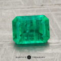 A 2.13-carat emerald-cut green gemstone is displayed on a light textured surface with the "Earth's Treasury" logo and text below.