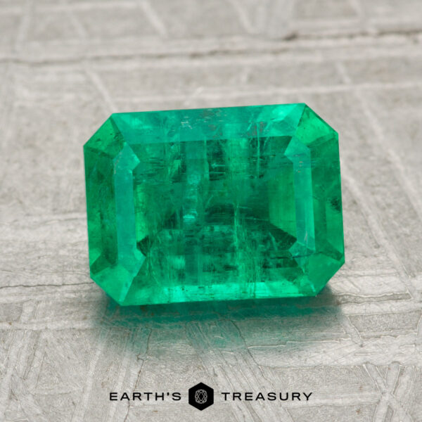 2.13-Carat Emerald A 2.13-carat emerald-cut green gemstone is displayed on a light textured surface with the "Earth's Treasury" logo and text below.