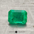 A 1.53-carat rectangular-cut green emerald is displayed on a light textured surface with the text "EARTH'S TREASURY" at the bottom.
