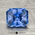 A 2.72-carat heated Ceylon sapphire with a faceted rectangular cut is displayed on a gray textured surface, featuring the "EARTH'S TREASURY" text below.