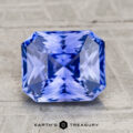 A 2.72-carat heated Ceylon sapphire, faceted in a rectangular asscher cut, is displayed on a textured light gray surface. The Earth's Treasury logo appears at the bottom of the image.