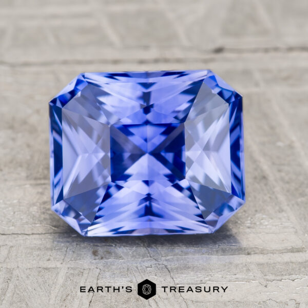 2.72-Carat Ceylon Sapphire (Heated) A 2.72-carat heated Ceylon sapphire, faceted in a rectangular asscher cut, is displayed on a textured light gray surface. The Earth's Treasury logo appears at the bottom of the image.