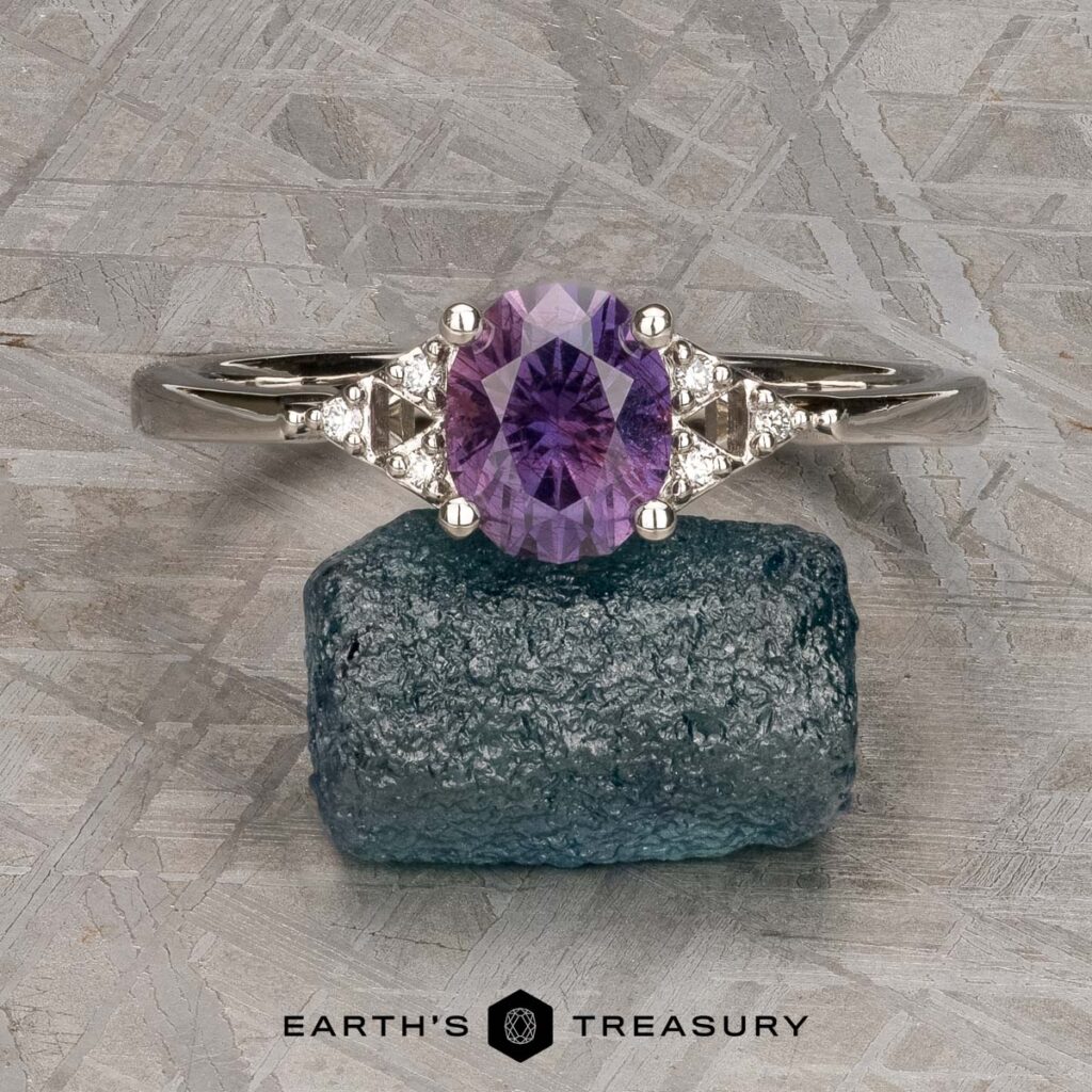 The "Osborn, Trevor [custom gallery]" silver ring features a purple gemstone and two small clear stones, displayed on a rough blue mineral with the "Earth's Treasury" logo below.
