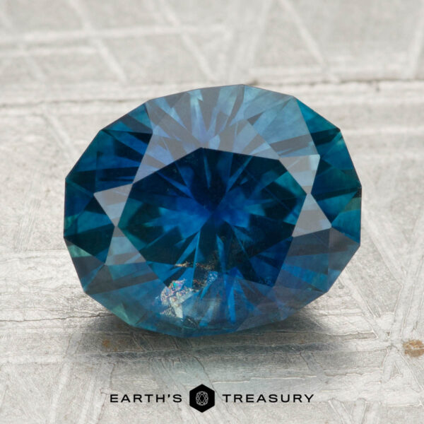 4.00-Carat Montana Sapphire (Heated) A 4.00-carat heated Montana sapphire, faceted in an oval shape, is displayed on a textured silver surface with the text "EARTH'S TREASURY" below.