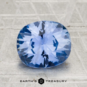 A 2.88-carat Ceylon sapphire with a cushion cut is shown on a textured gray surface, featuring the "Earth's Treasury" text below.
