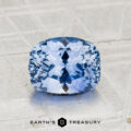 A faceted, cushion-cut 2.20-Carat Ceylon Sapphire rests on a textured gray surface with the text "EARTH'S TREASURY" below. This dazzling gemstone captivates with its vivid hue and exceptional clarity.
