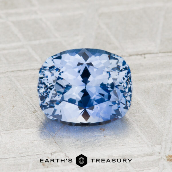 2.20-Carat Ceylon Sapphire A faceted, cushion-cut 2.20-Carat Ceylon Sapphire rests on a textured gray surface with the text "EARTH'S TREASURY" below. This dazzling gemstone captivates with its vivid hue and exceptional clarity.