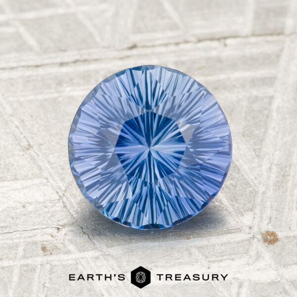 A round, faceted 1.89-carat Ceylon Sapphire gemstone is displayed on a textured gray surface with the text "Earth’s Treasury" at the bottom.