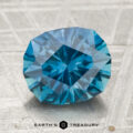 A 3.60-carat heated Montana sapphire is displayed on a textured surface with the "Earth's Treasury" logo and text at the bottom.