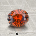 A 2.08-carat oval-cut Montana sapphire (heated) with deep orange and brown hues rests on a textured metallic surface; "EARTH'S TREASURY" appears below.