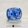 A faceted 2.09-carat Cornflower Blue Sapphire cushion-cut gemstone from "I see the strange light but it seems to come through at every an" rests on a textured gray surface, with "EARTH'S TREASURY" printed beneath.