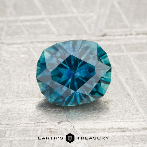 1.33-Carat Montana Sapphire (Heated) A 1.33-carat heated Montana sapphire is shown on a light, textured surface with "Earth's Treasury" at the bottom.