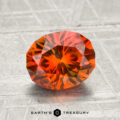 2.06-carat oval-cut orange Montana sapphire (heated) displayed on a textured surface, with "EARTH'S TREASURY" at the bottom.