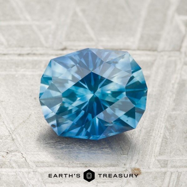 2.14-Carat Montana Sapphire (Heated) A 2.14-carat heated Montana sapphire with a hexagonal cut is displayed on a metallic surface, with "EARTH'S TREASURY" written below.