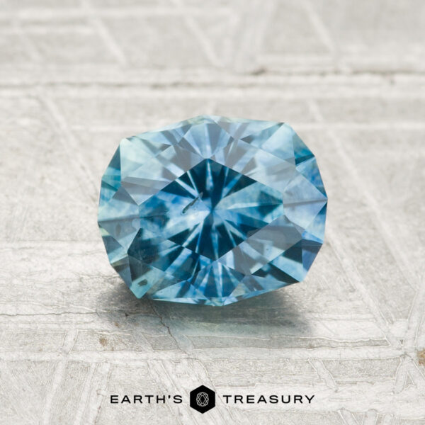 1.48-Carat Montana Sapphire (Heated) A 1.48-carat heated Montana sapphire is displayed on a textured, light surface with “Earth’s Treasury” below it.