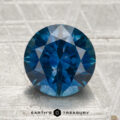 2.75-carat round brilliant-cut heated Montana sapphire displayed on a textured surface, featuring the "Earth's Treasury" logo and text at the bottom.